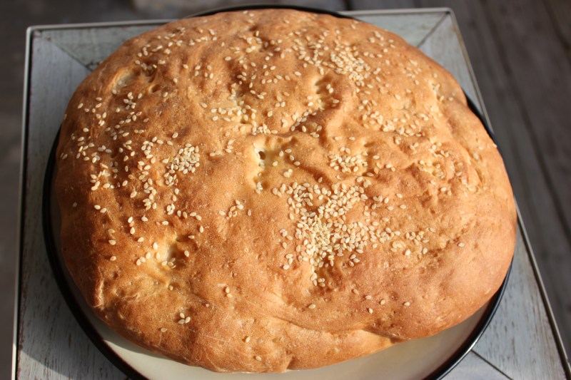A giant muffuletta bun that takes up a whole plate.