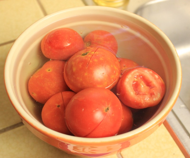 Use boiling water method to peel tomatoes. First you slice their skin and then dunk them in boiling water for about 30 - 45 seconds followed with an ice bath.